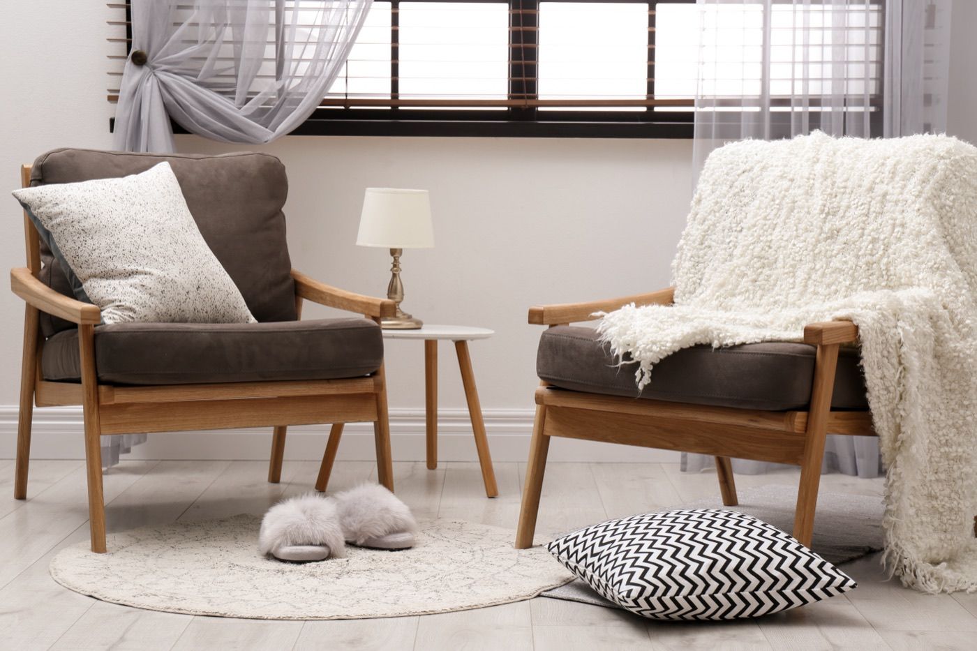 Two armchairs with soft pillows and a throw in a bright, quiet room.